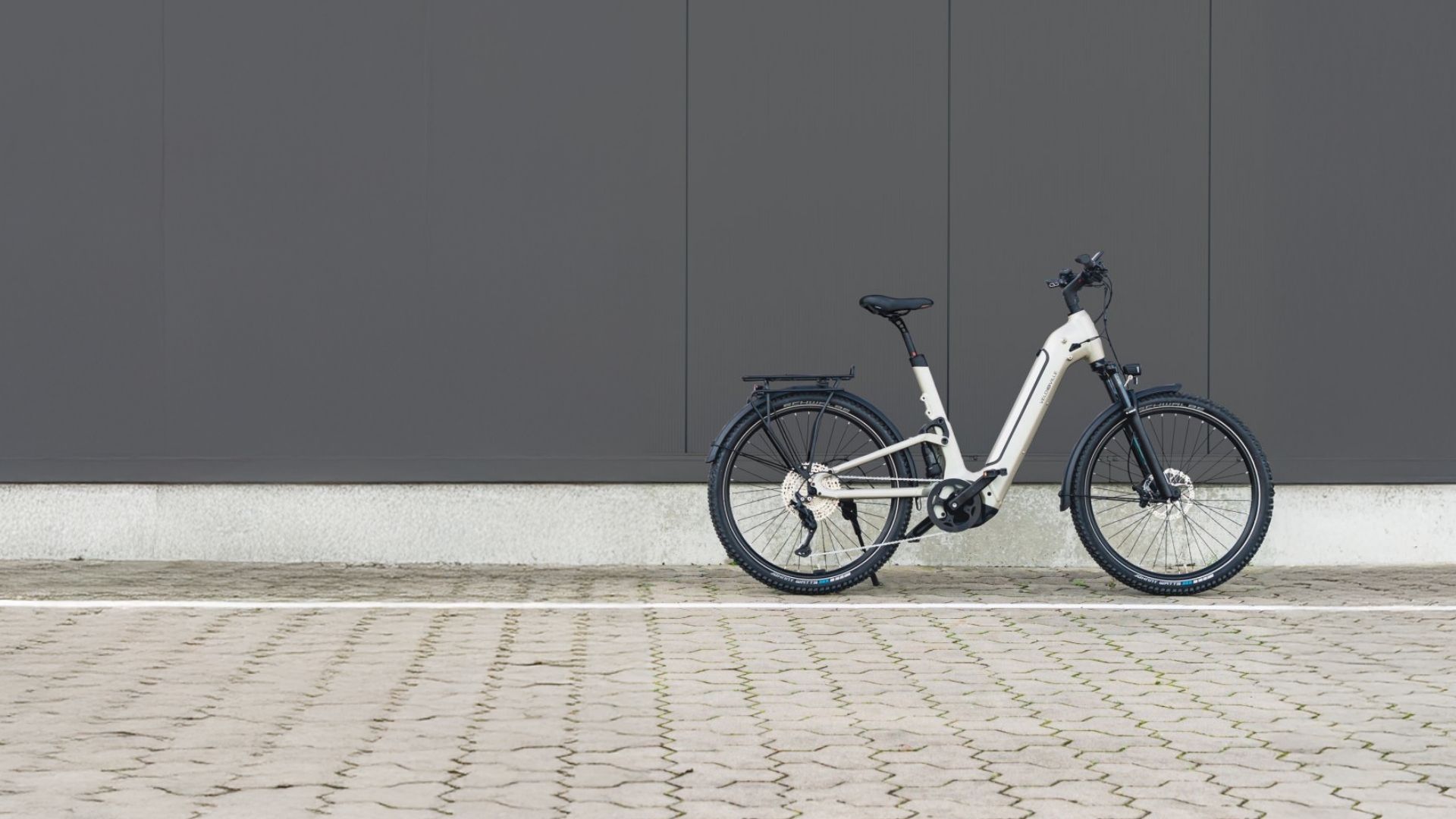 Vollgefedertes E-Bike vor grauer Wand